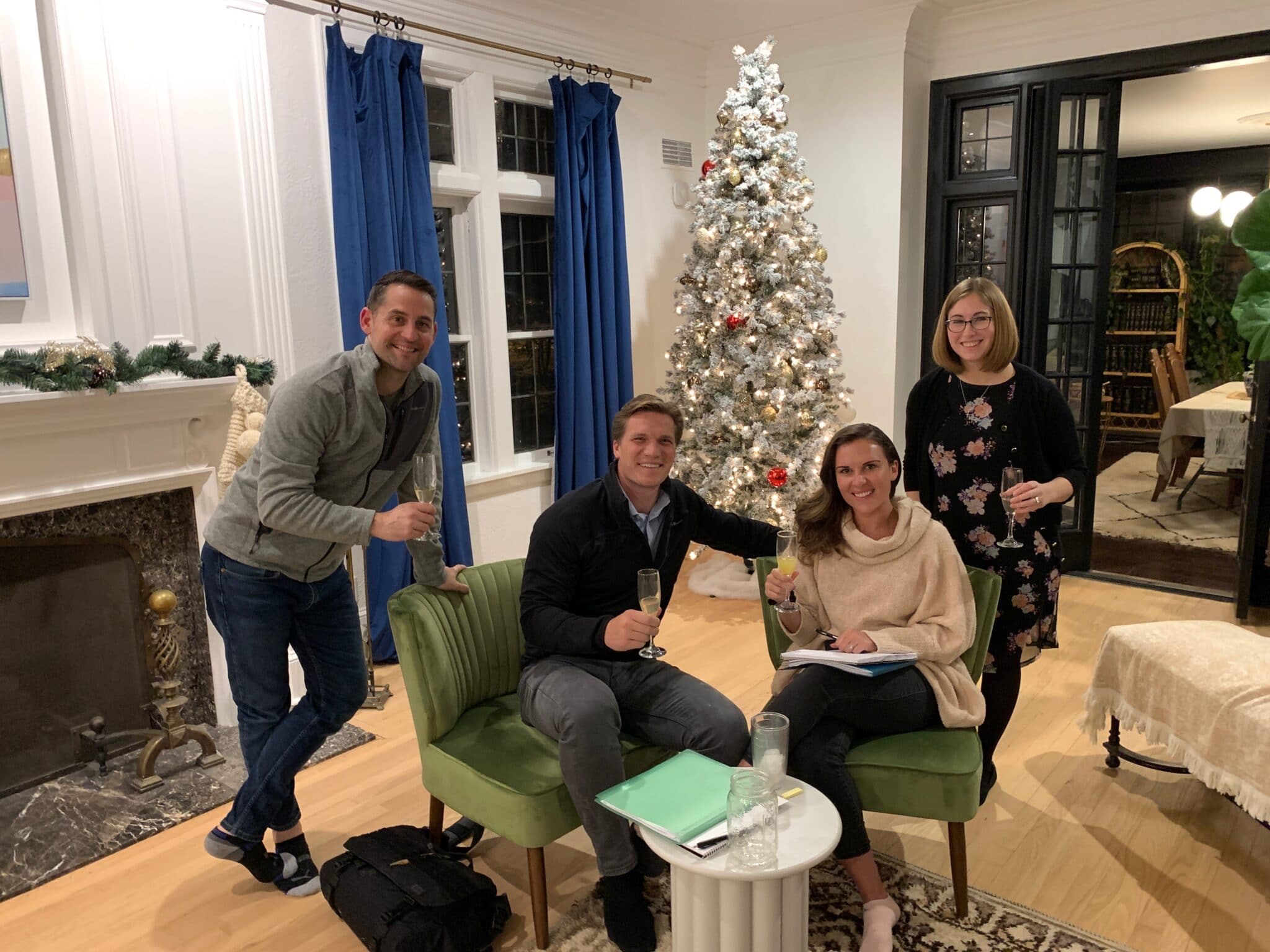 Charista and Kevin of Thoughtful Franchise Brokers in decorated living room, standing next to 2 new clients sitting in chairs