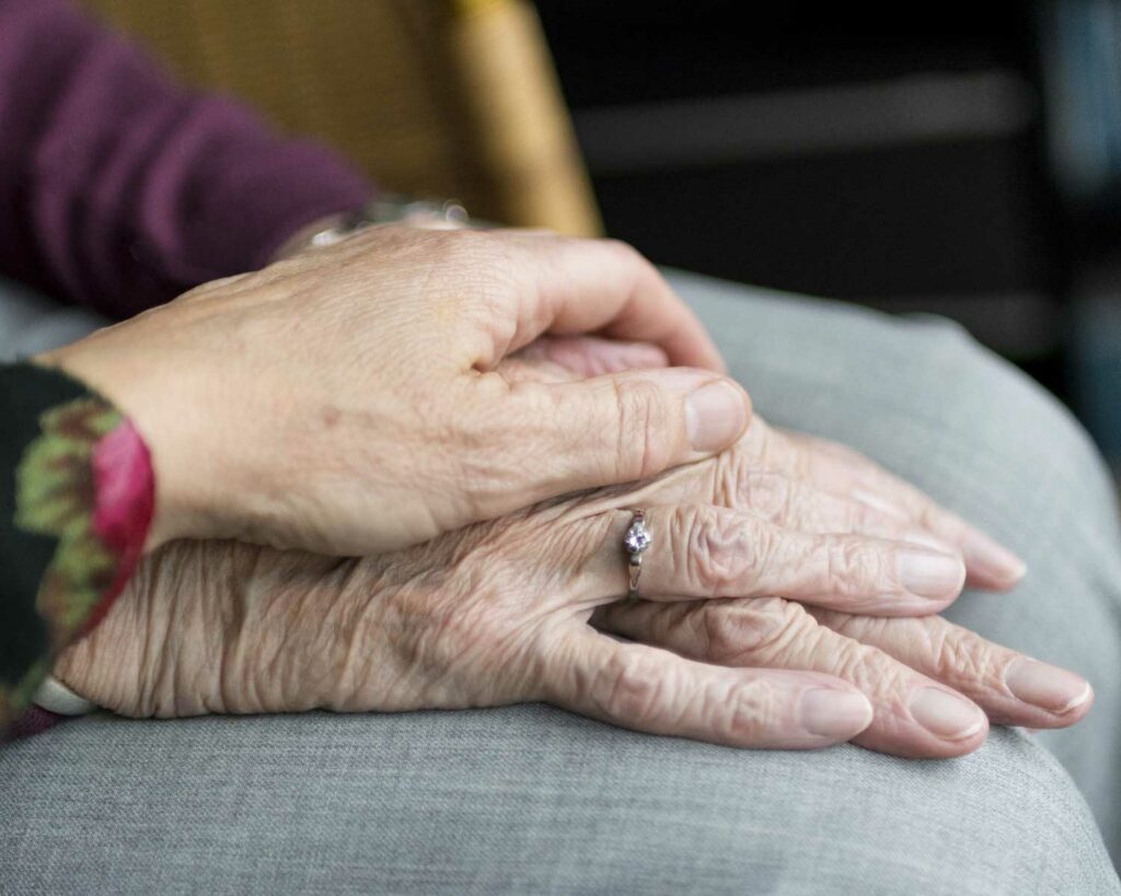 A hand resting on 2 other hands that are elderly
